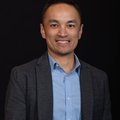 Hao Banh with short dark hair, a blue collared shirt, and grey blazer