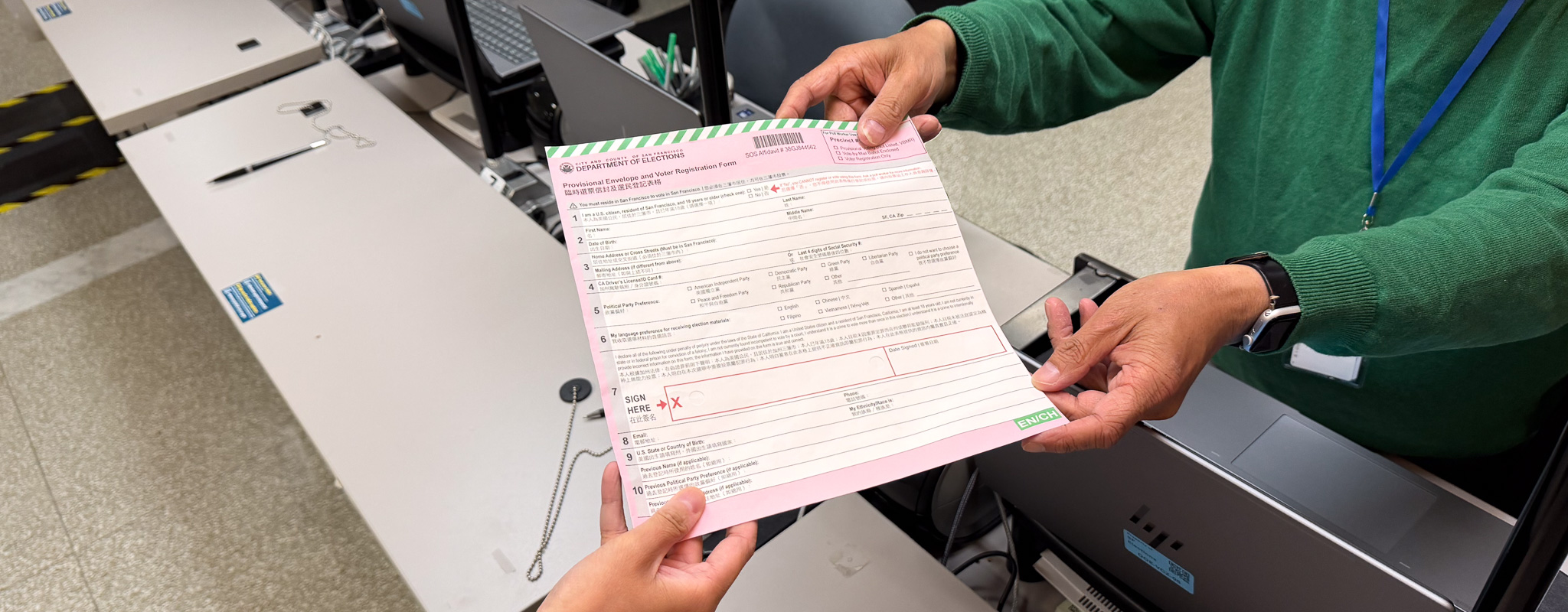 An election worker handing a provisional envelope to a voter