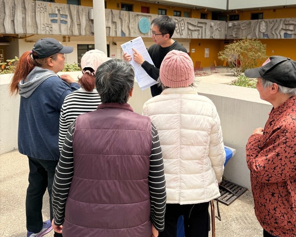 An Outreach member explaining how to fill out a registration form to a group of residents.