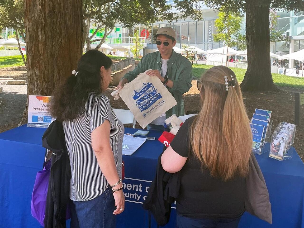 Elections outreach staff communicating with voter at resource table.