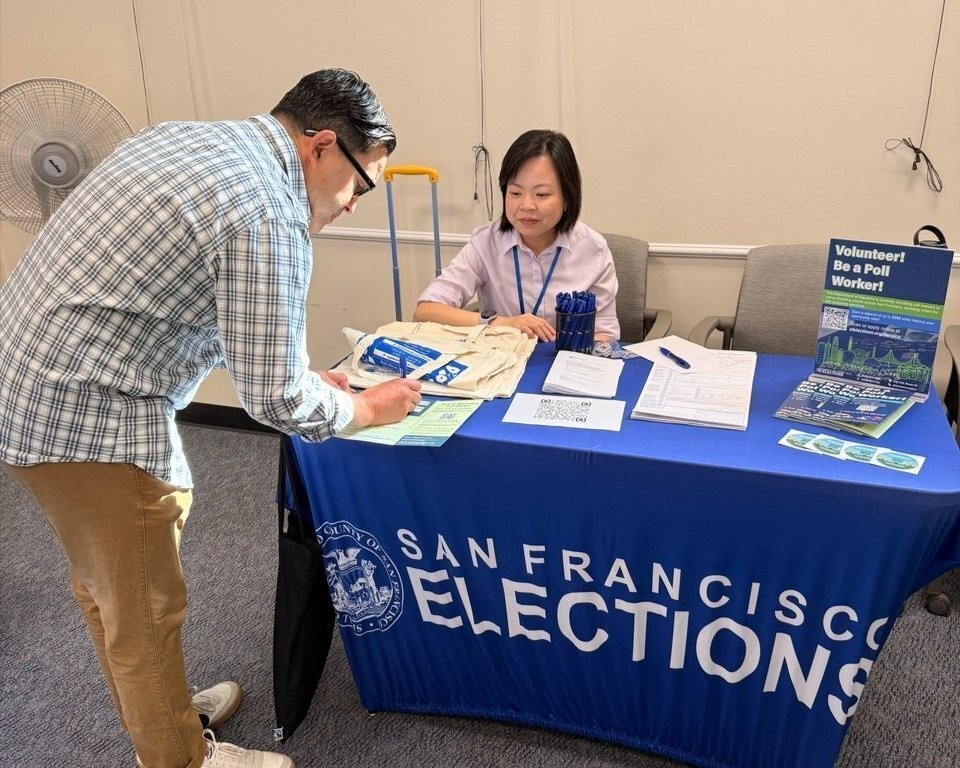 SF resident reading flyers at Elections Outreach table.