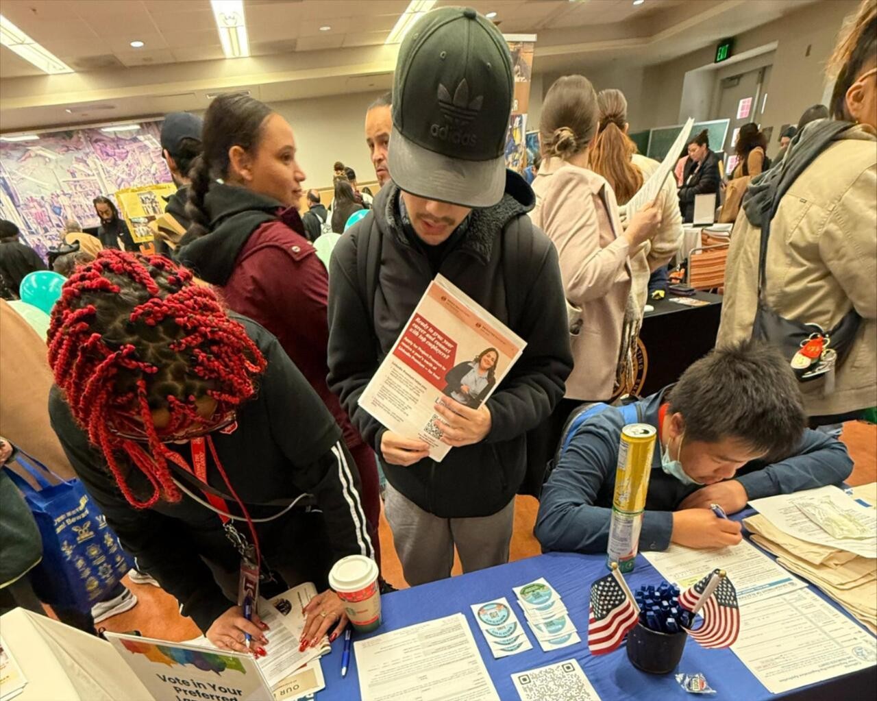 Three SF residents registering to vote at a voter resource table.