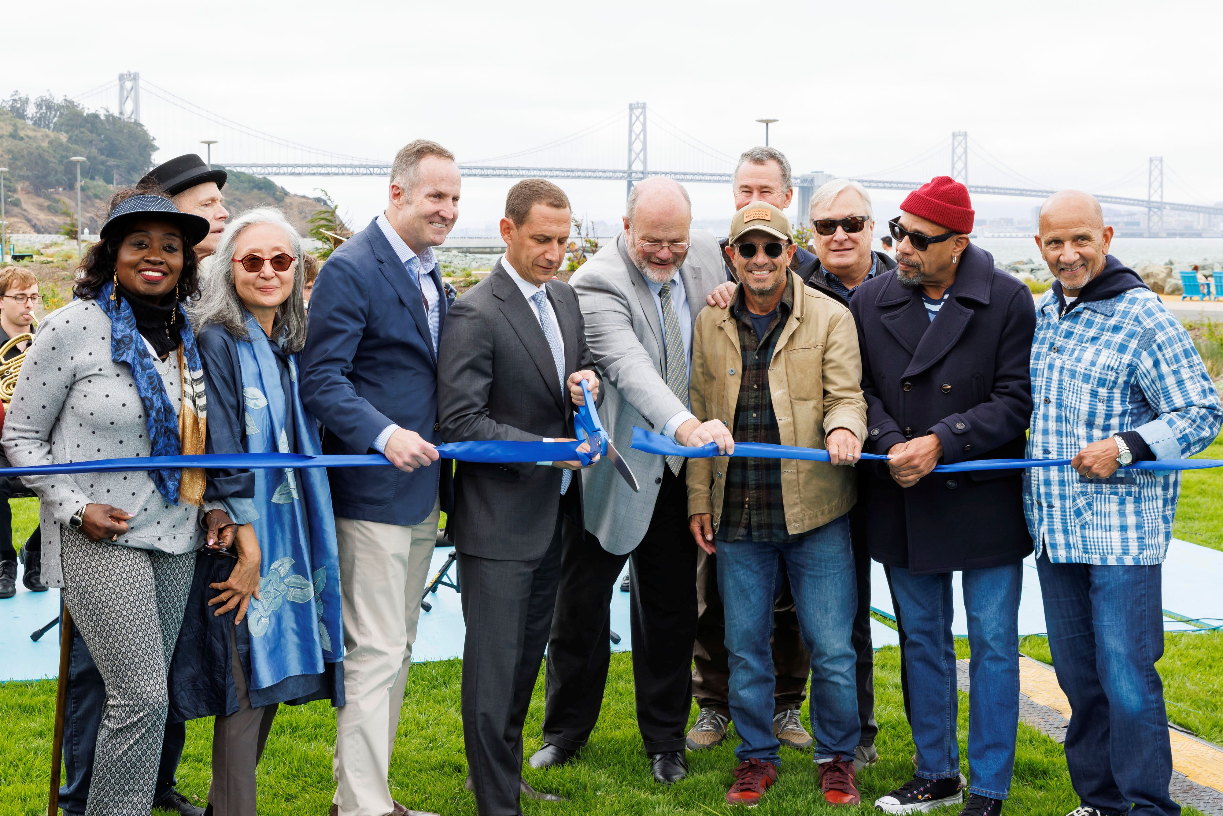 Mayor Lurie and a group of dignitaries cut a blue ribbon with oversized scissors