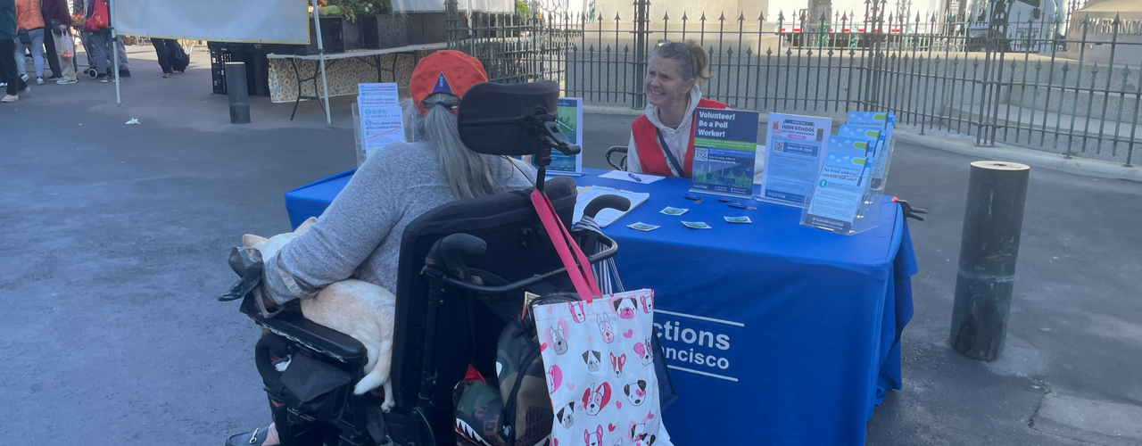 Elections staff at an outreach event speaking with an SF resident in a wheelchair