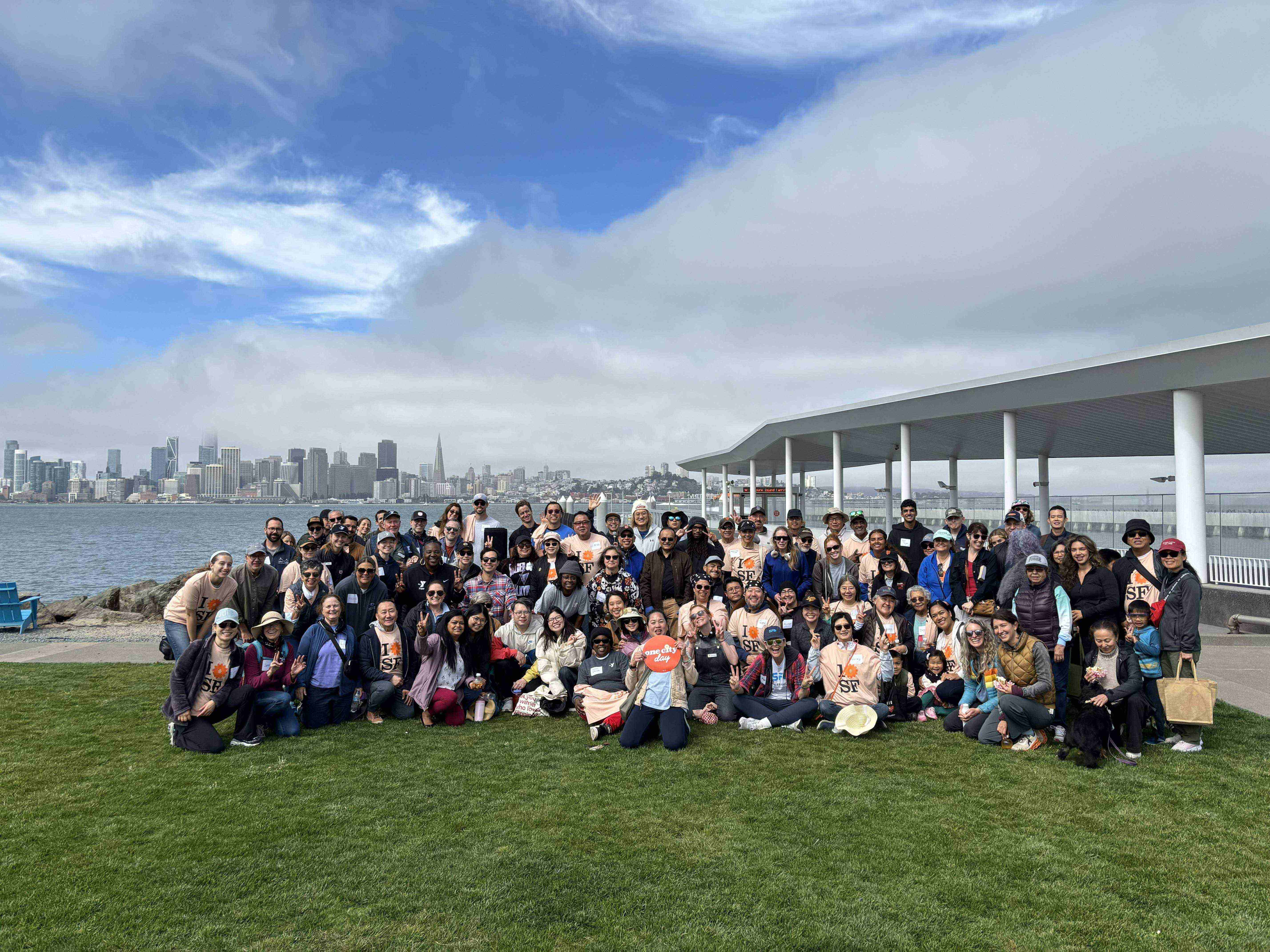 Large group of people pictured in front of SF skyline on Treasure Island