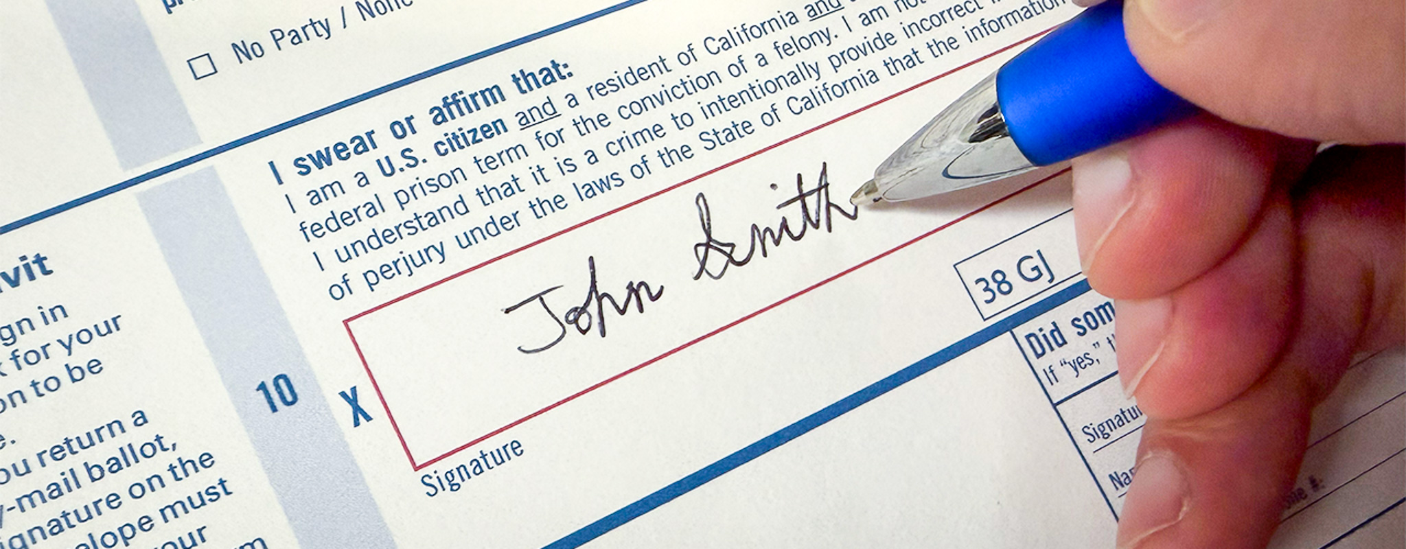 Close up photo of someone's hand updating their signature on a registration form.