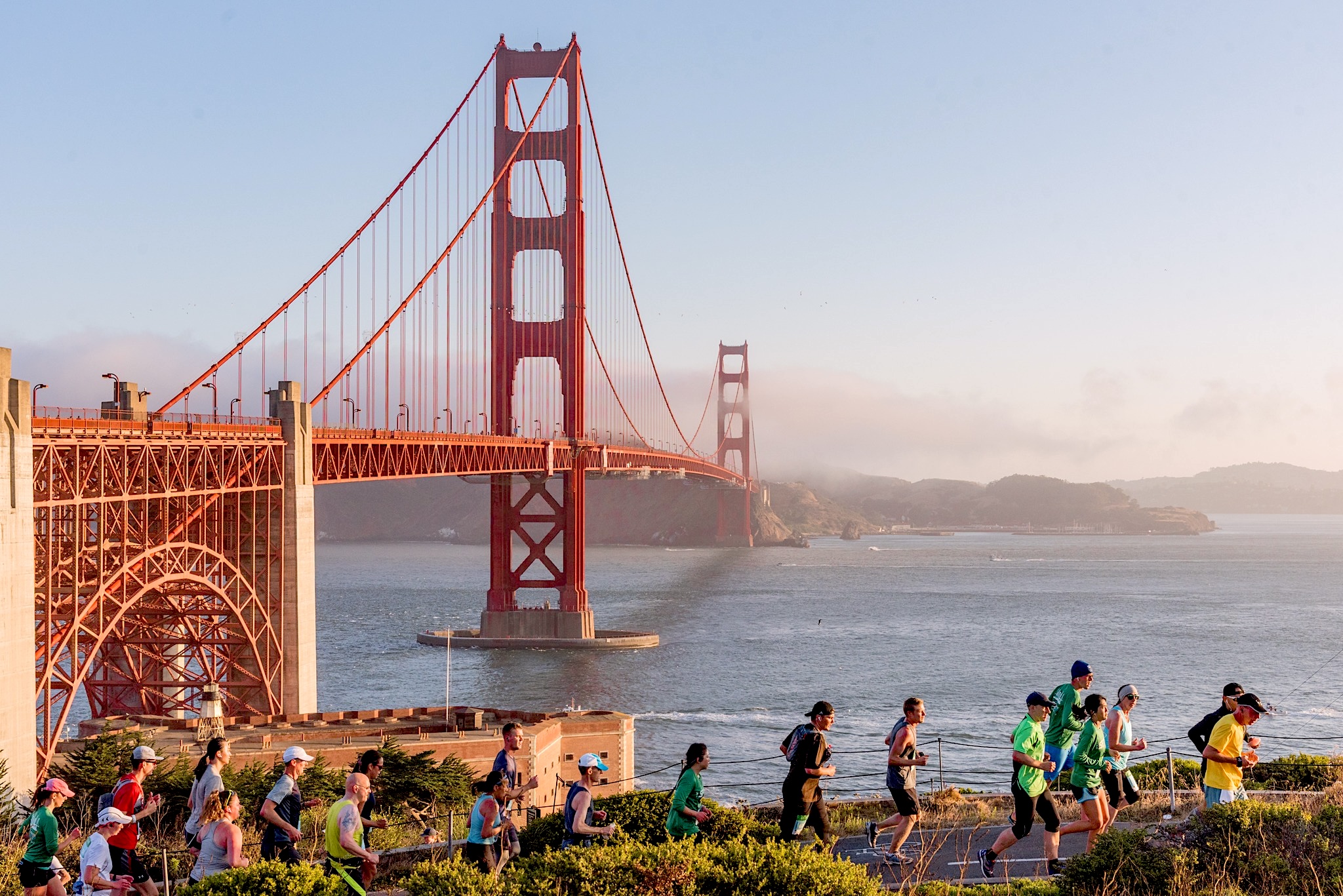 Marathoners running on a sunny morning with the Golden Gate Bridge in the background