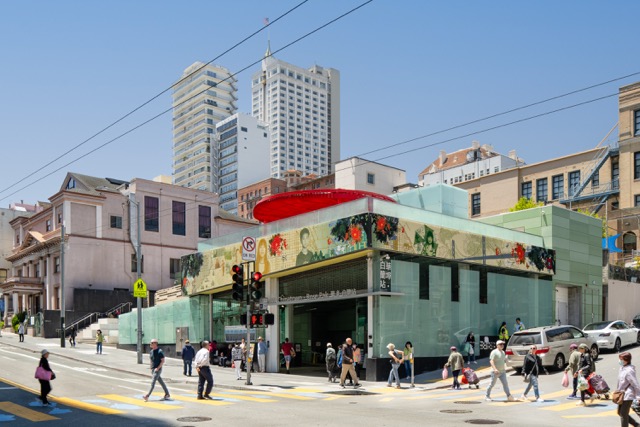 Chinatown–Rose Park station entrance in San Francisco, with pedestrians crossing and city buildings rising behind the modern glass structure.