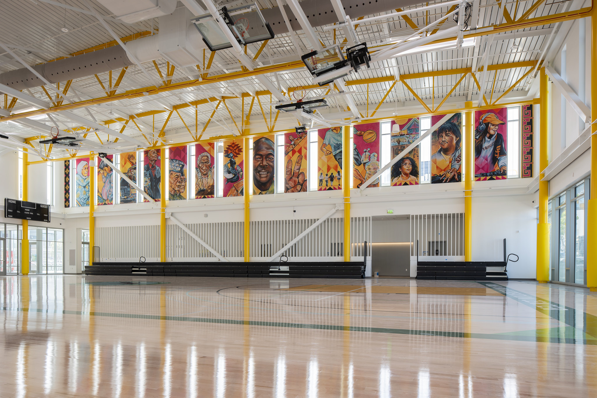 wide shot of recreation center that includes shiny wooden floors, yellow columns and tapestries with artwork on 14 banners draping down from the ceiling