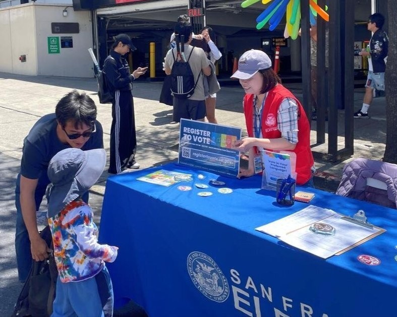 SF Elections outreach member speaking to an SF resident and their toddler