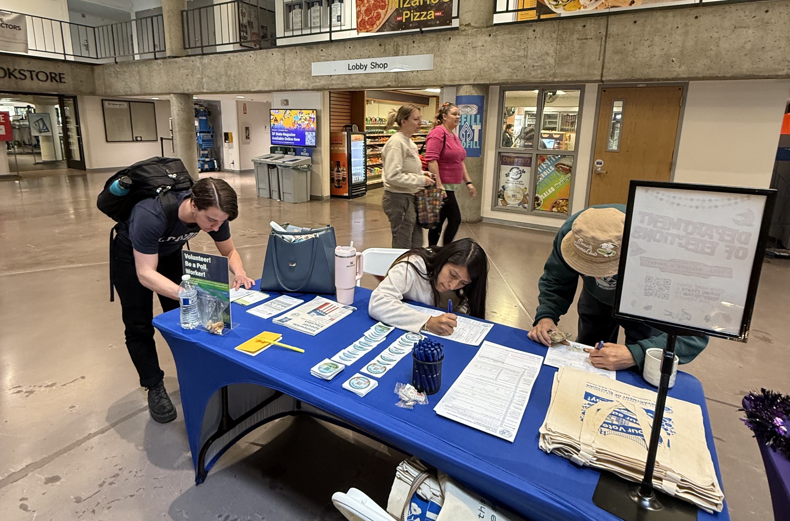 3 students registering to vote at an Outreach event.
