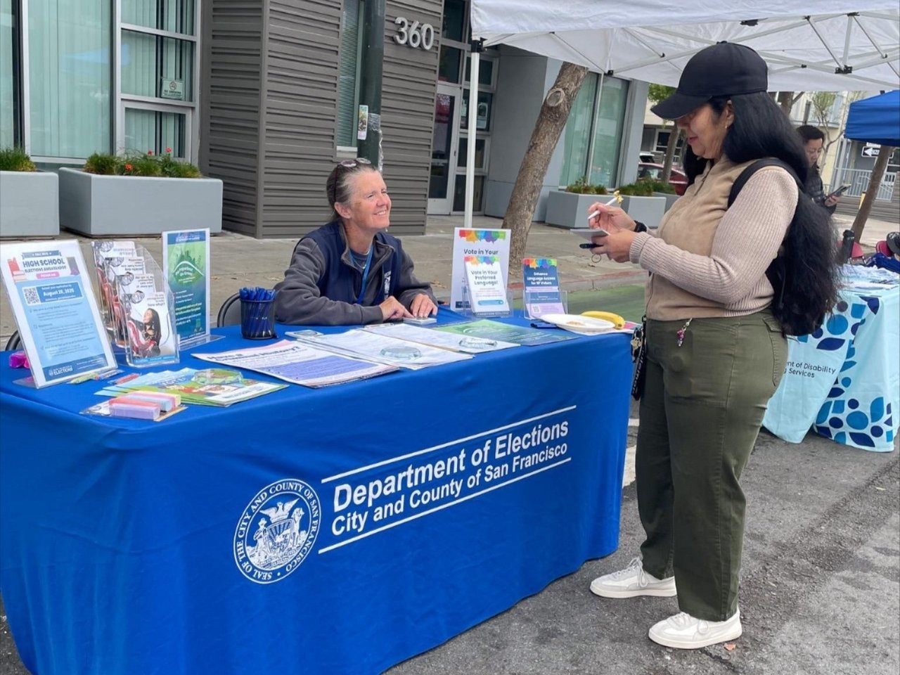Elections outreach staff communicating with voter at resource table