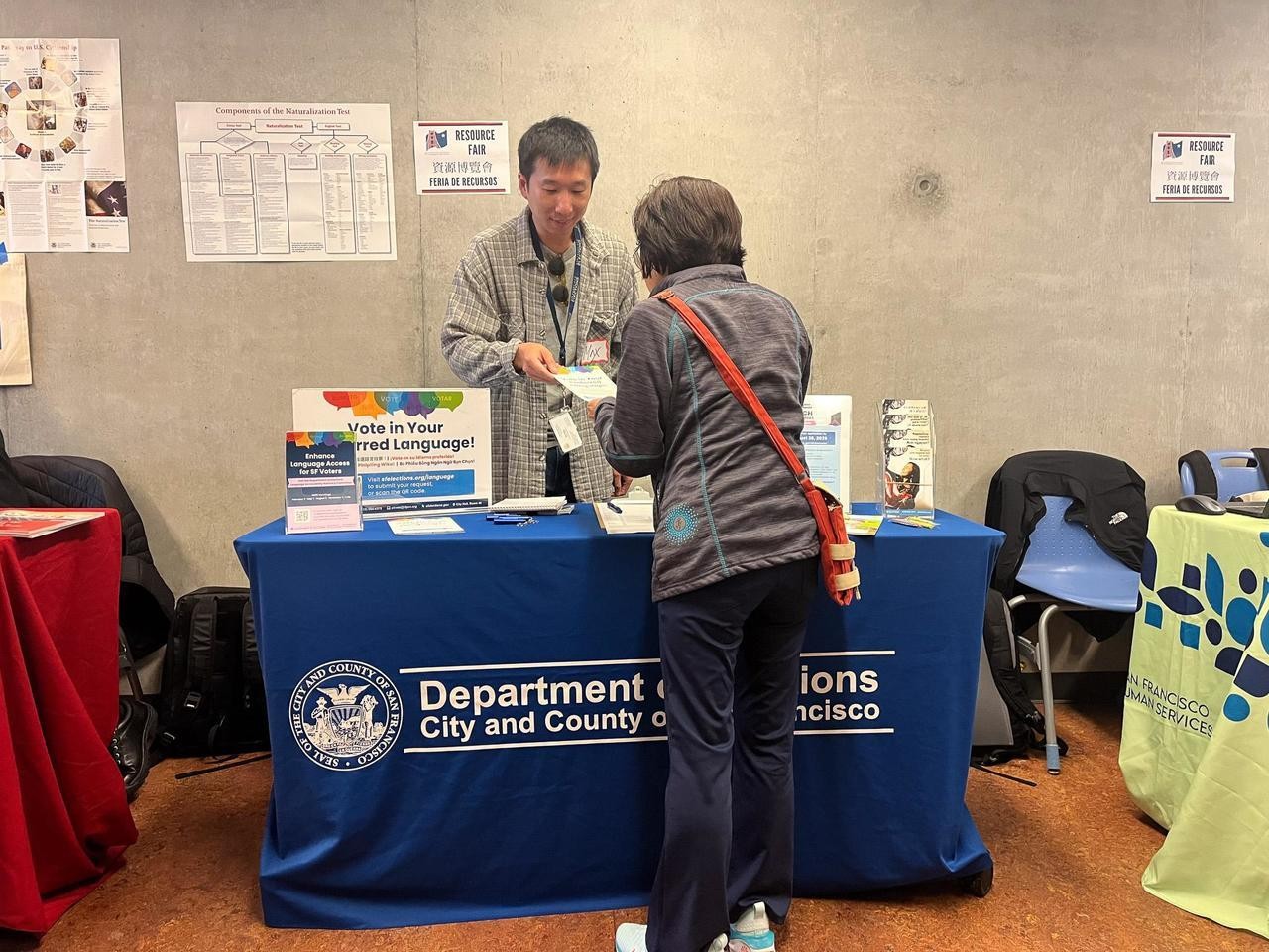 Elections outreach staff handing flyer to voter at resource table