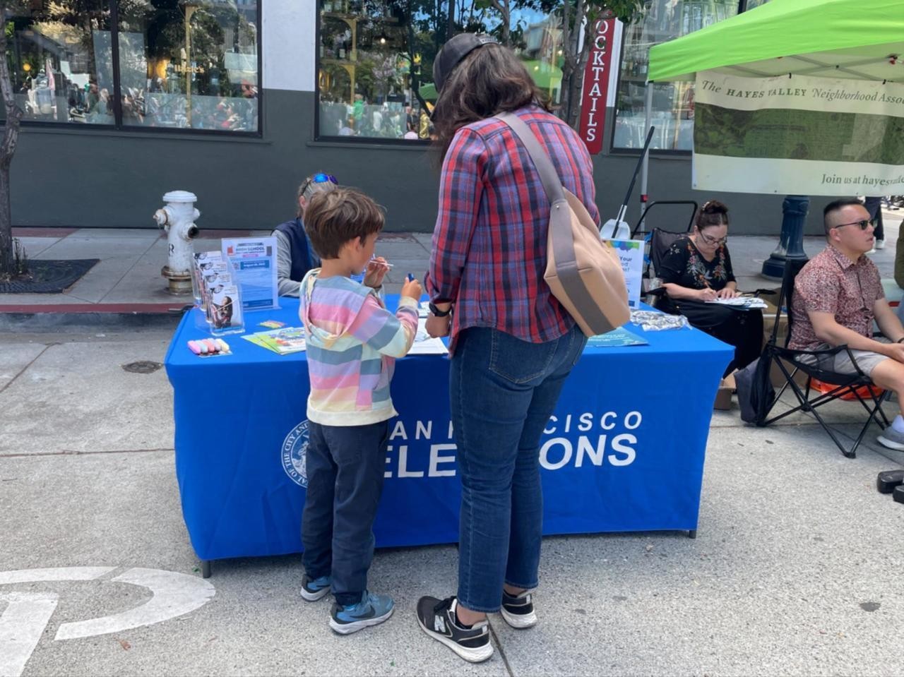 Mother and child looking at flyer and resources at elections resource table
