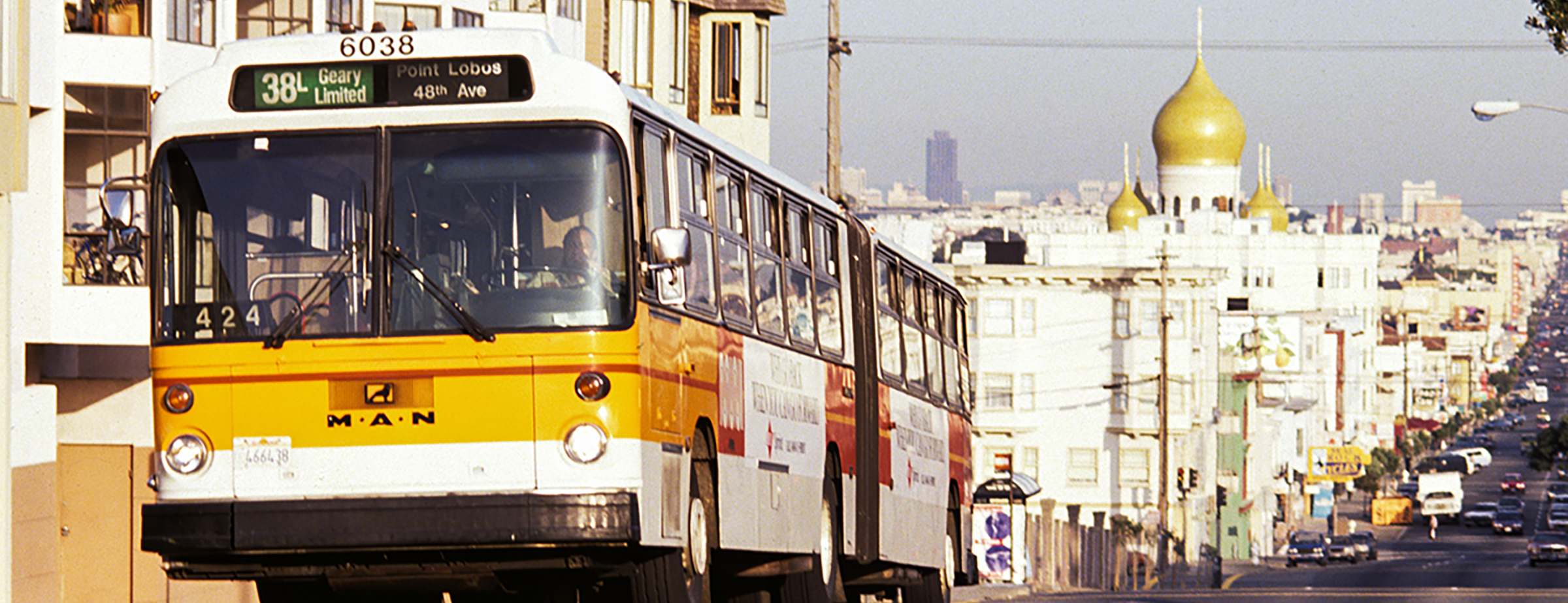 A 38-Geary Muni bus in 1993, driving up an incline, with a view of San Francisco's Outer Richmond district behind it.
