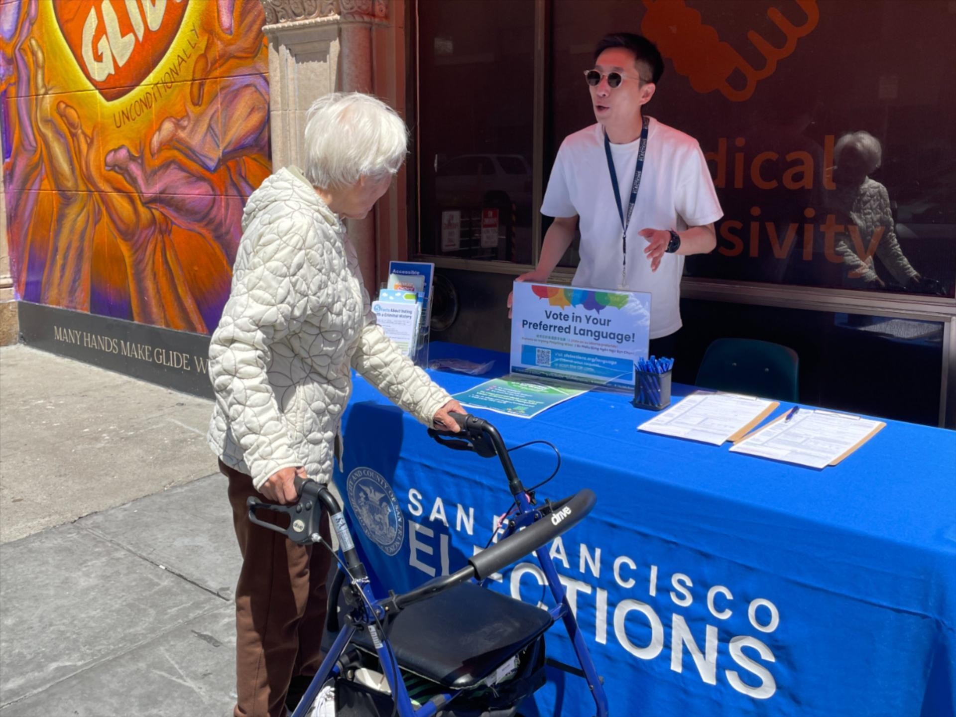 An Elections Outreach member speaking with a senior SF resident with a walker.