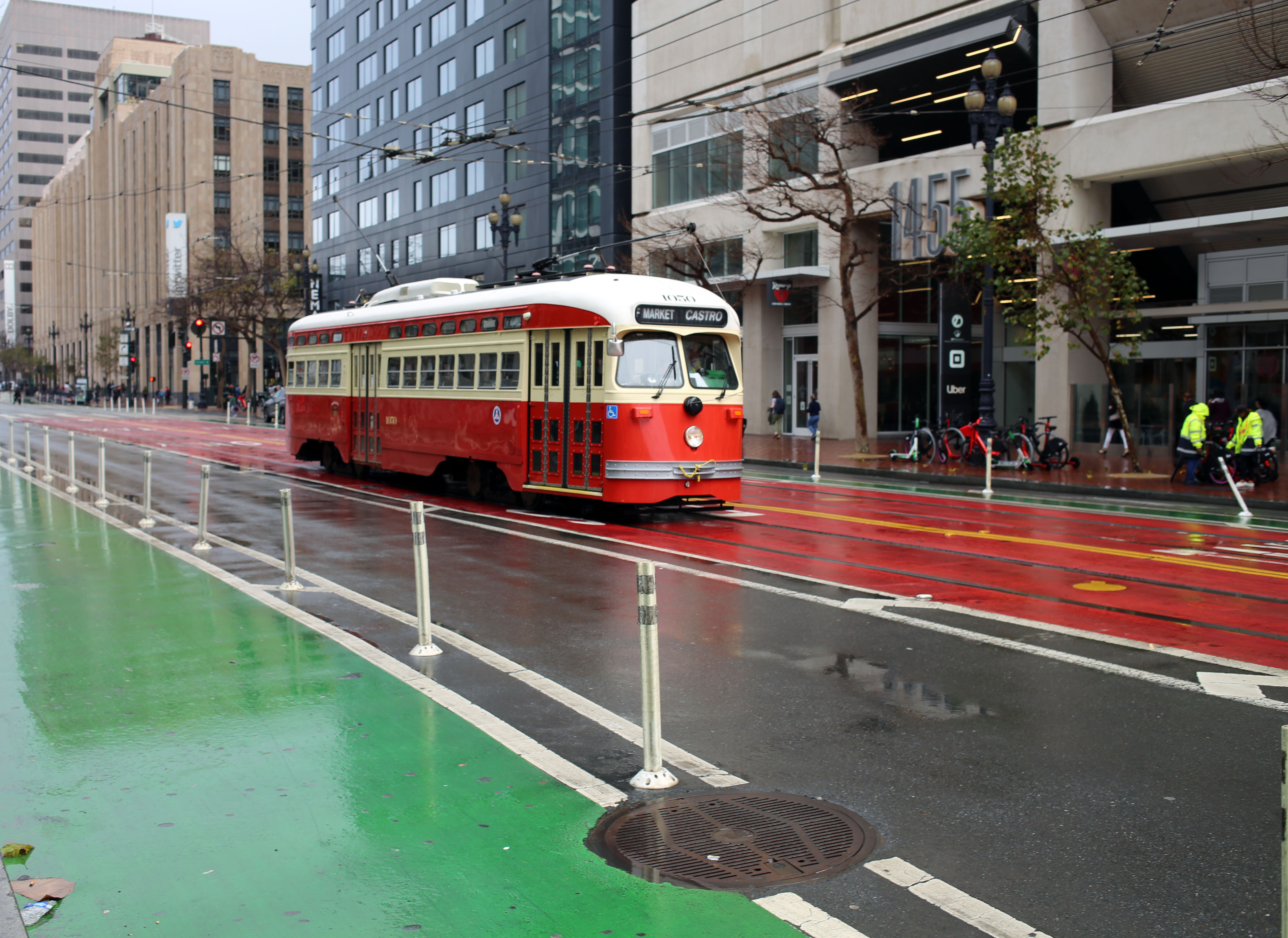 A red and beige trolley drives down a wet San Francisco street