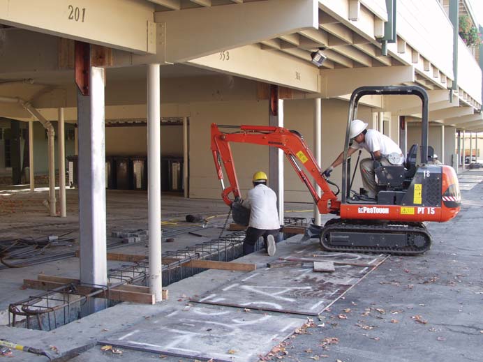 Two people working on a construction site on the lower level of an apartment building.