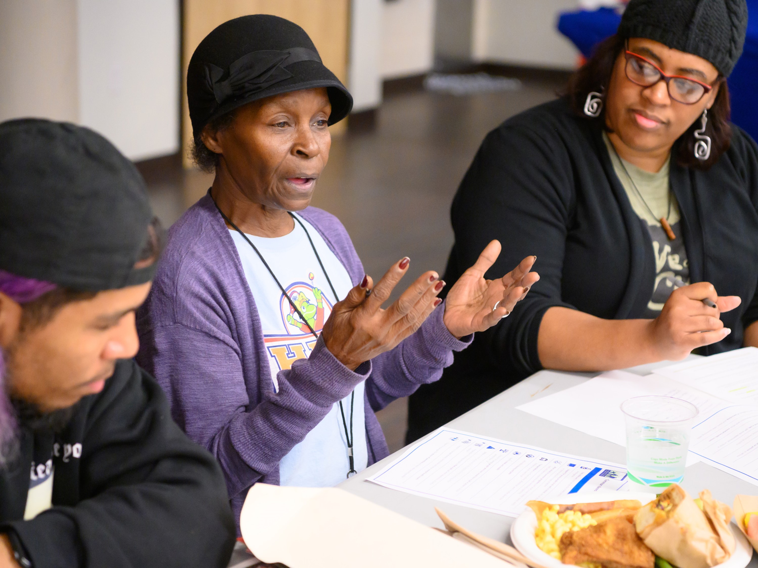 a woman talking while a man listens and a woman takes notes