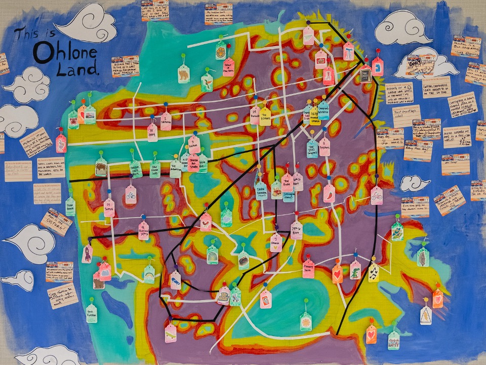A painted map of San Francisco. People have added handwritten tags with their memories of specific places