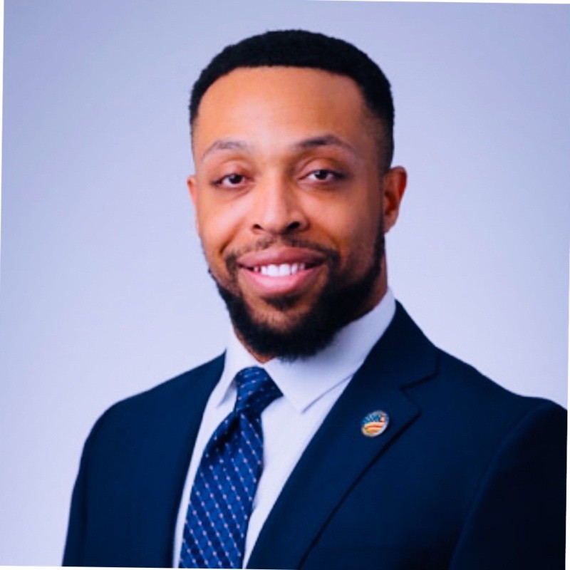 Headshot of Commissioner Obai Rambo in a dark blue suit and tie