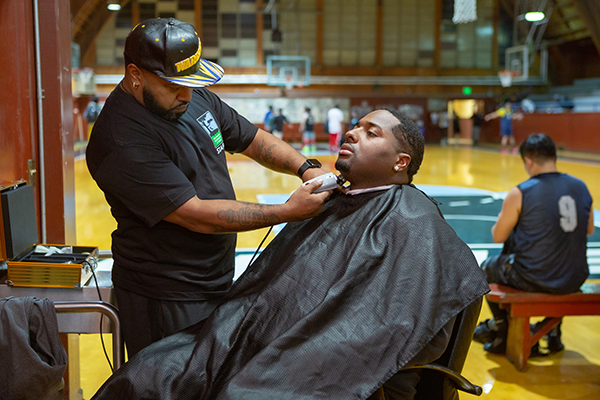 A barber trims the beard of a customer.