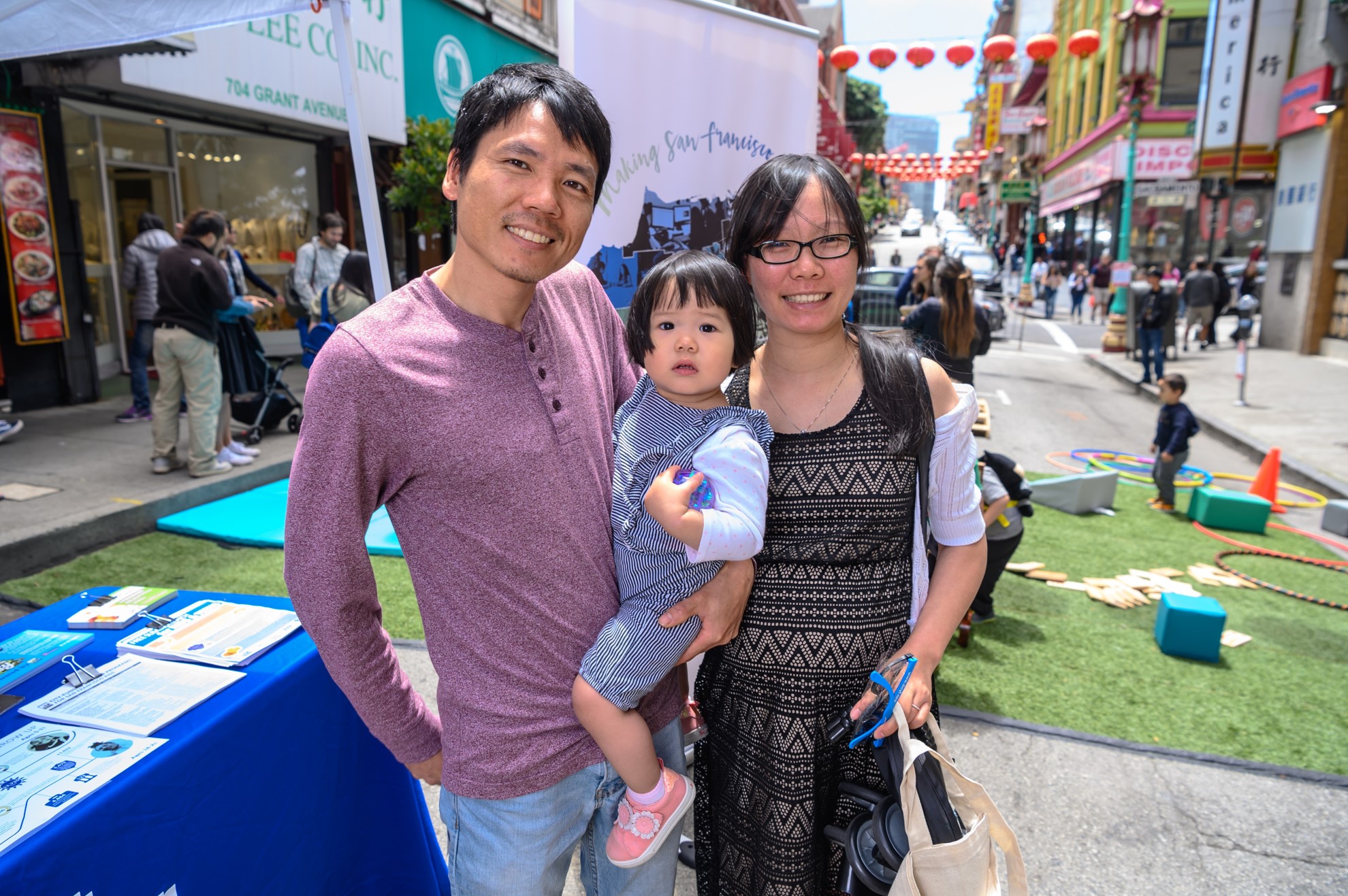 A father, mother and their young child standing at an outdoor event