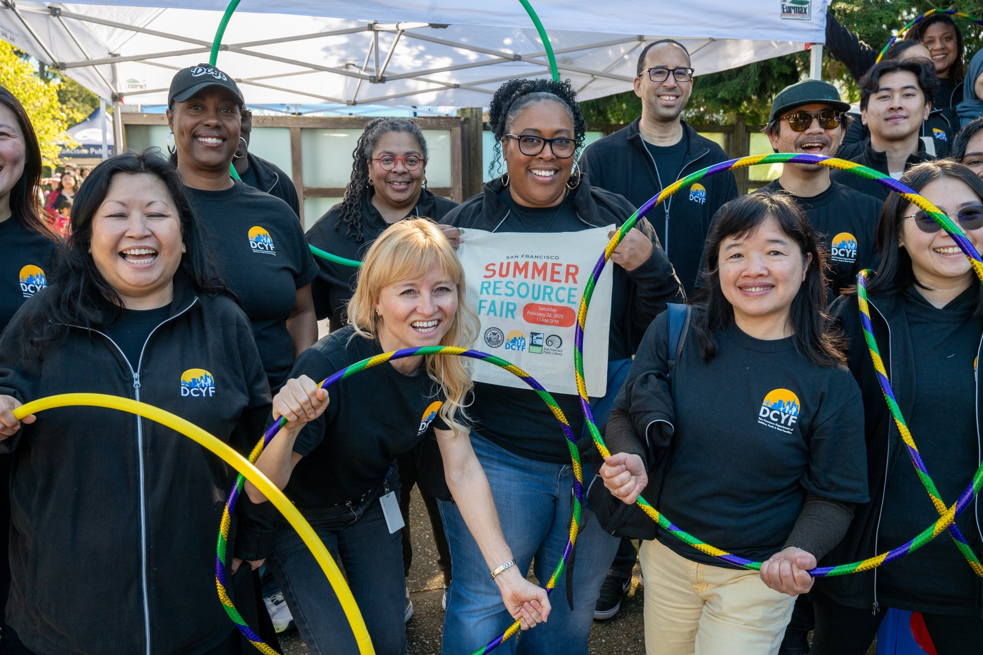 A group of people holding a tote bag that says DCYF Summer Resource Fair on it.