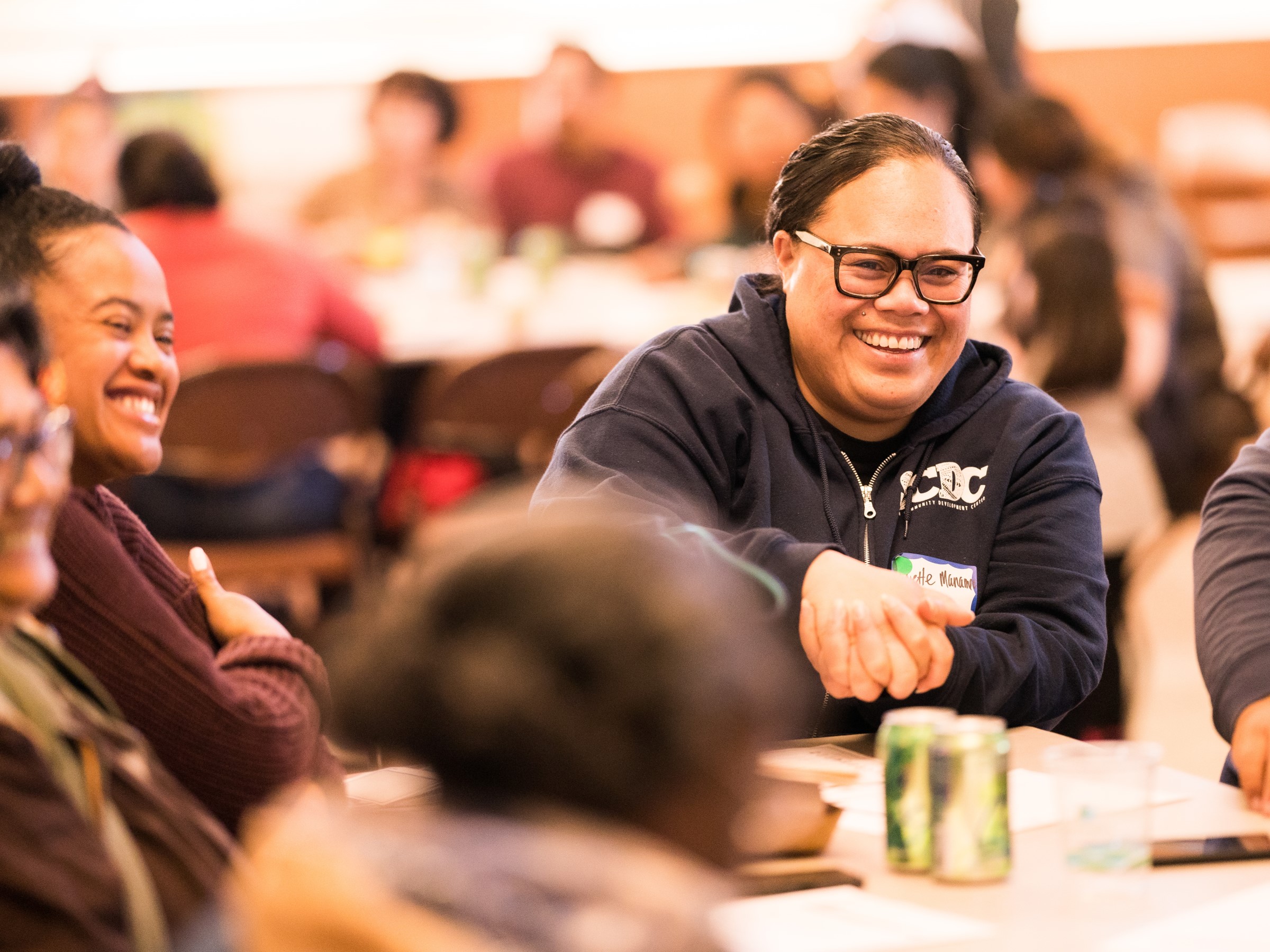 two women smiling at a table with other people