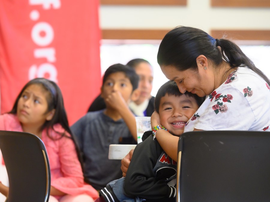 Niyakap ng isang ina ang kaniyang anak na lalaki habang nakaupo sa malapit ang kaniyang anak na babae