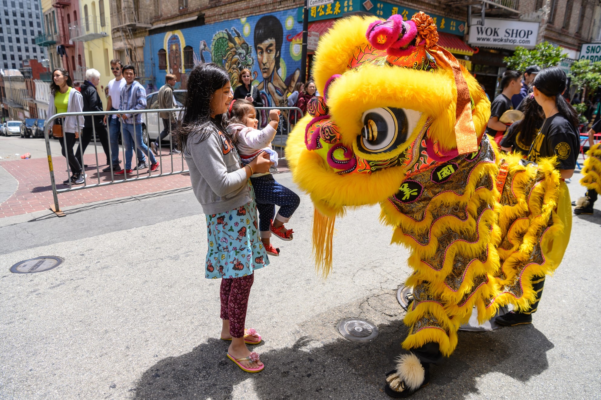 A girl holding a small child next to a Chinese dragon float.