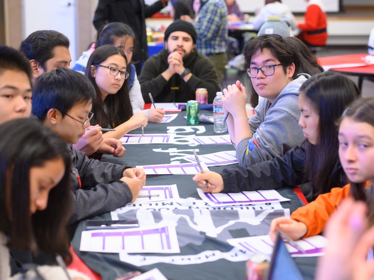 a group of young people sitting around a table talking