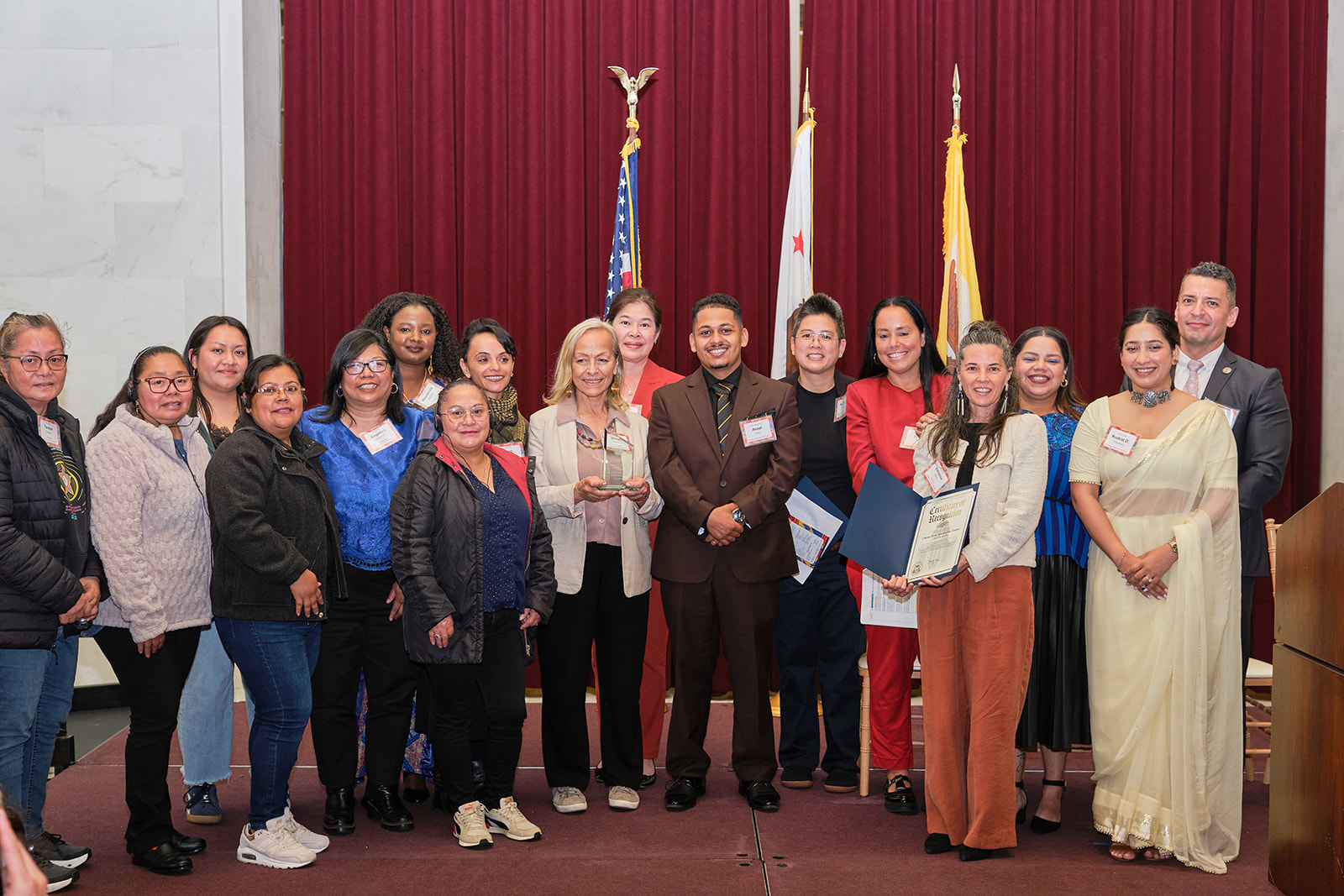 A group of leaders from the San Francisco Immigrant Legal and Education Network (SFILEN) pose on stage at City Hall with their Immigrant Leadership Award.