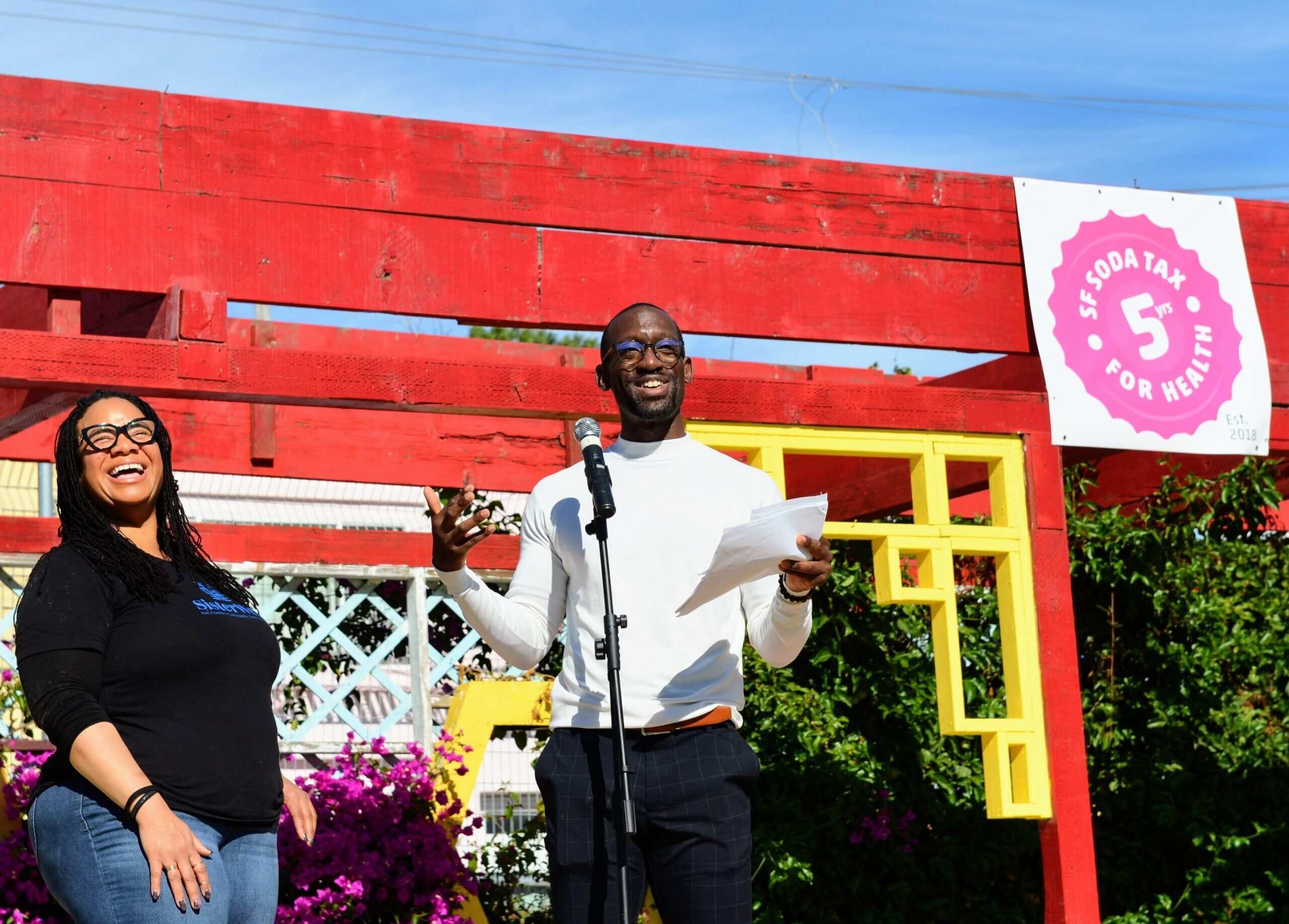 Two people smiling and posing together at the 5-year soda tax celebration at Florence Fang Community Farm.