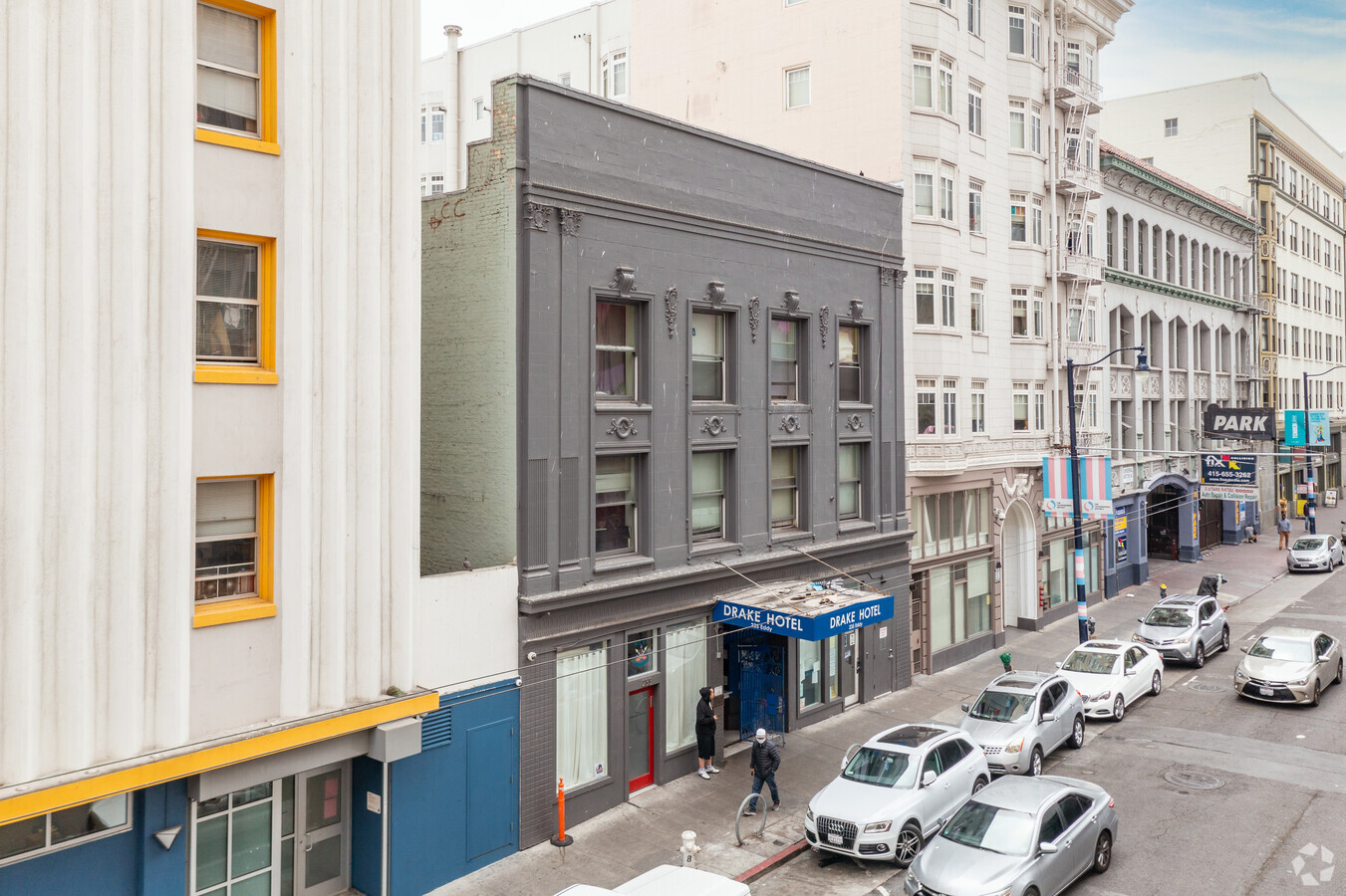 Grey Building with a blue awning that reads DRAKE HOTEL, standing between two white buildings - grey building is the New Horizons - Drake Hotel Program