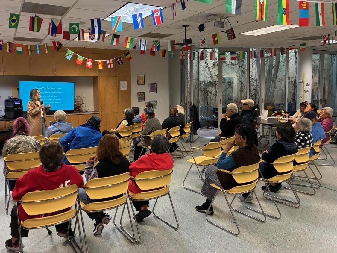 A group of 20 seniors watching a presentation by an Elections Outreach Staff member.