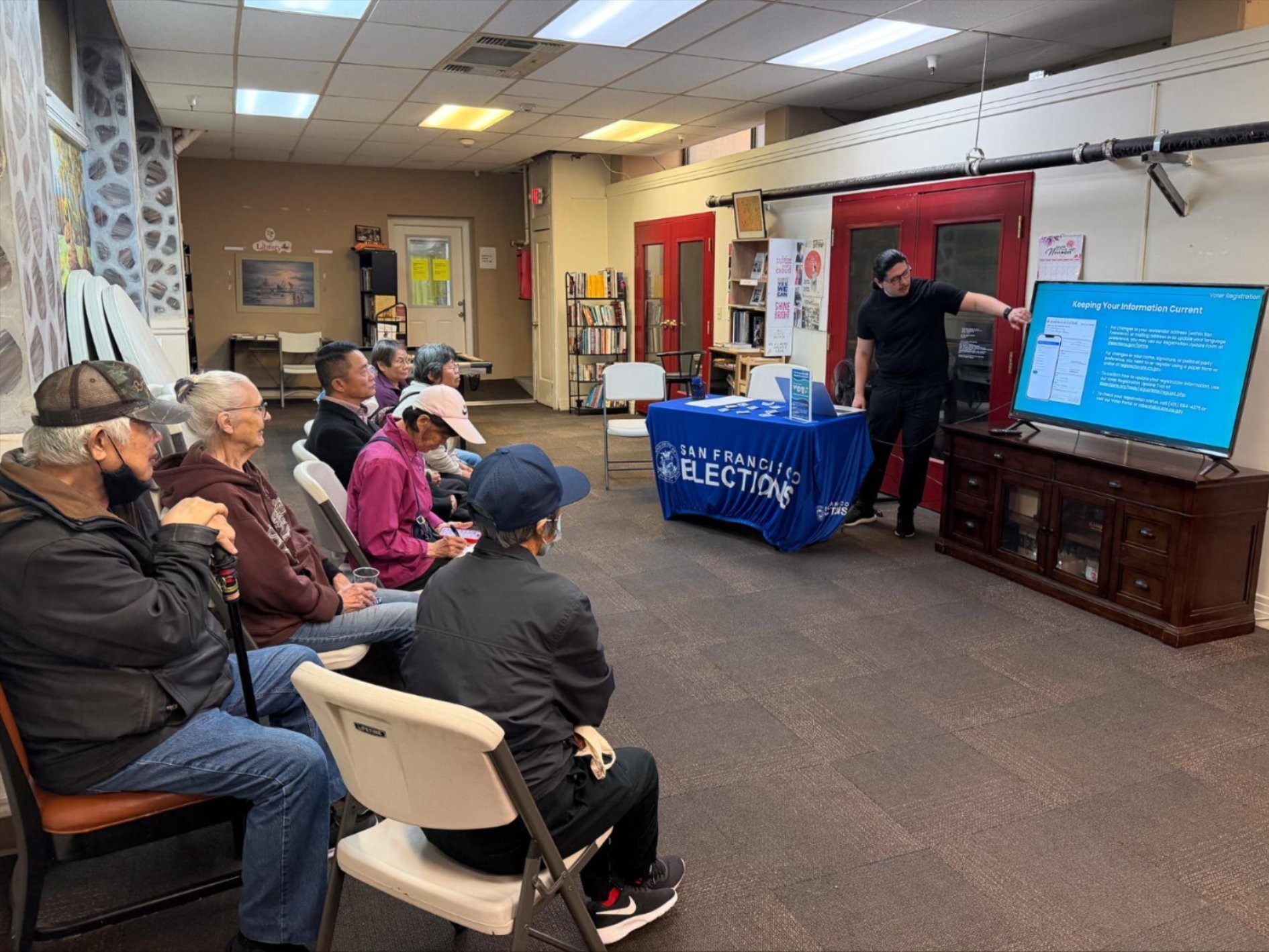 A group of 7 seniors watching an election presentation by an Elections Outreach Staff member.
