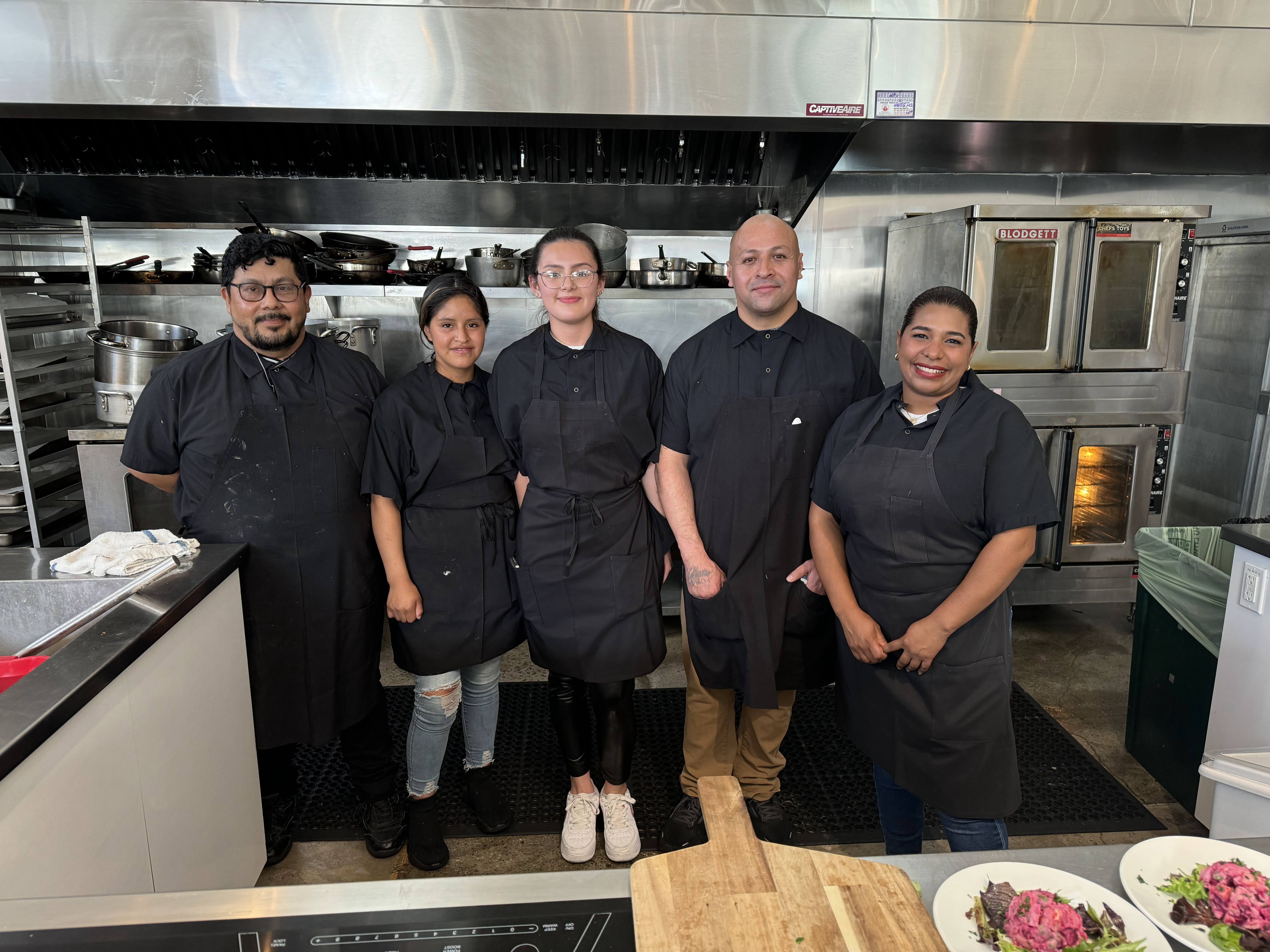 a group of culinary apprentices from Farming Hope pose in an industrial kitchen