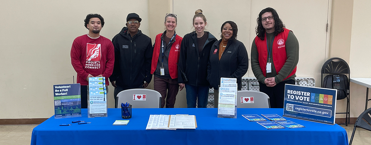 Group picture of 2 Department of Elections staff with staff from Project Homeless Connect at an Outreach event.
