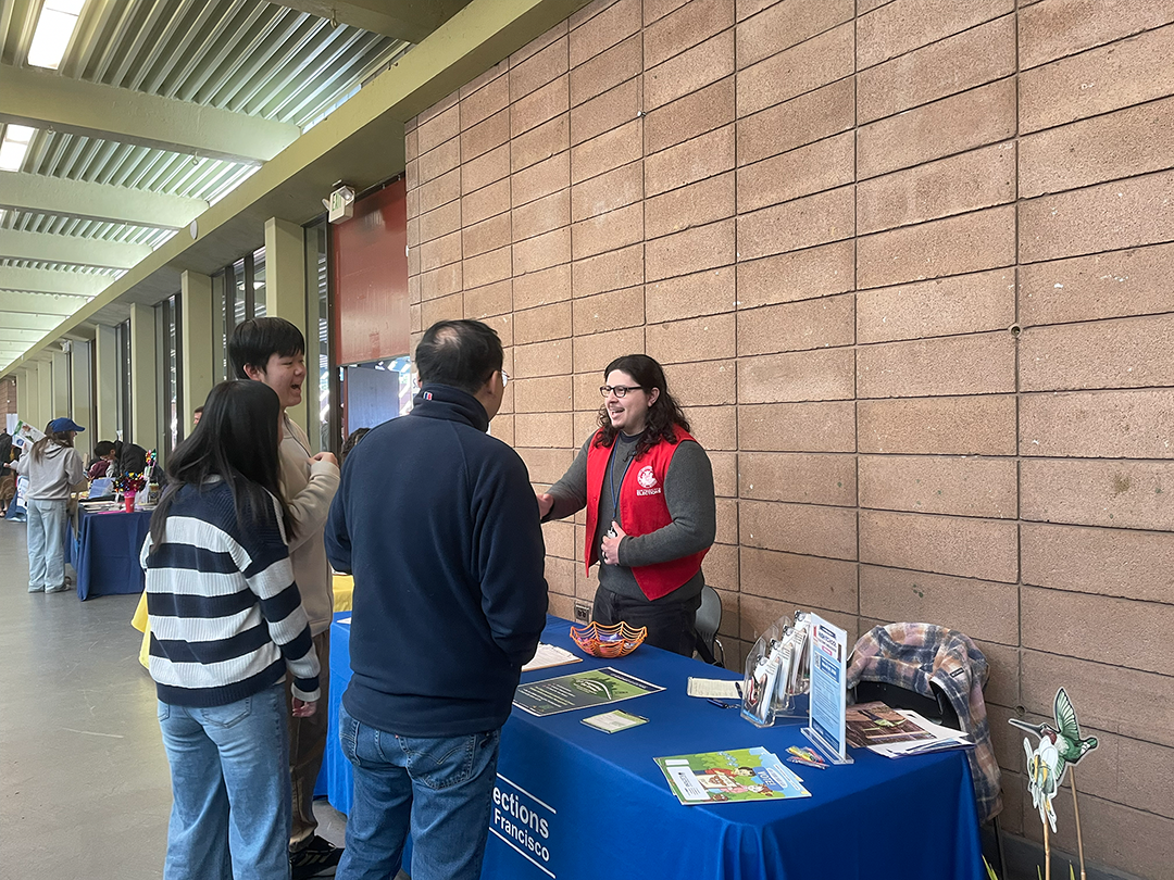Picture of Elections Outreach staff speaking with a family at the Summer Resource Fair