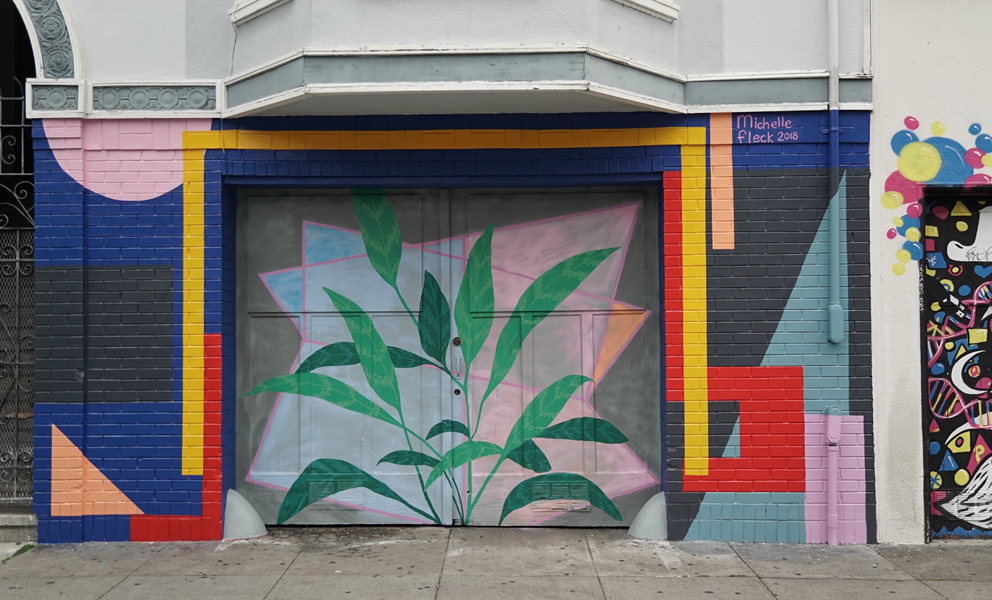 Colorful geometric mural with abstract shapes and plant forms integrated across a building façade and garage doors.