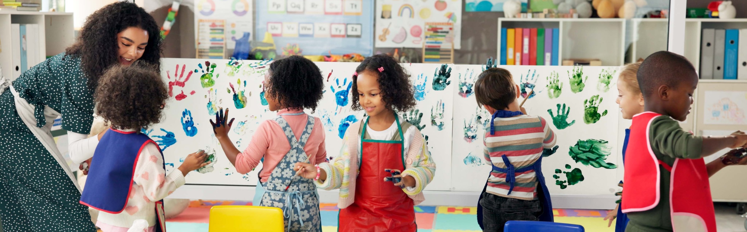 Handprint, painting and children with paper in classroom for creative lesson, education and development. School, students and kids learning with colors for fun activity, art project and motor skills