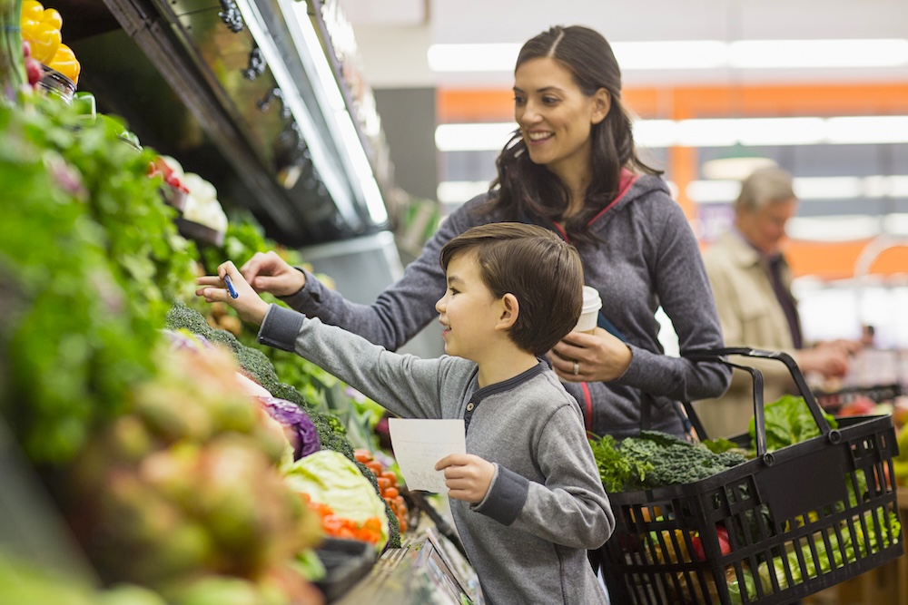 Mother and son shopping for vegetables at supermarket