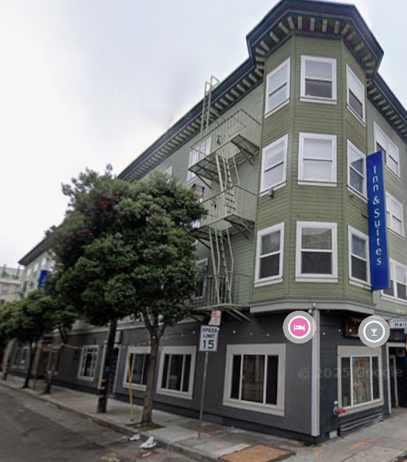 Green corner buidling with big windows and a blue sign that reads Inn & Suites - the HER house expansion is located here