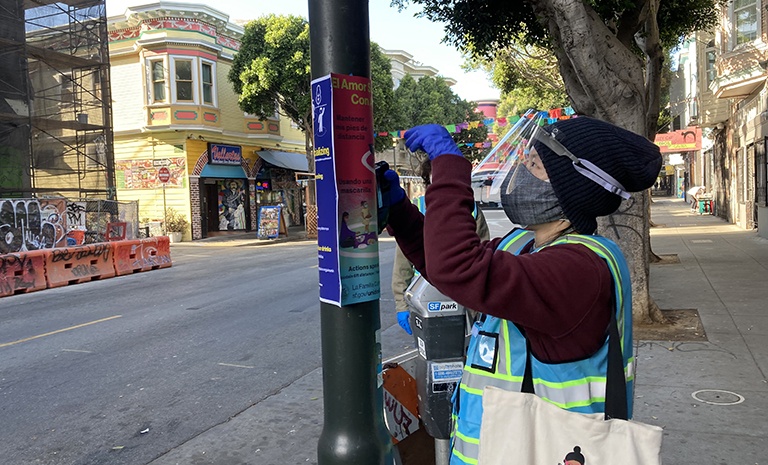 Person taping a poster on street lamp
