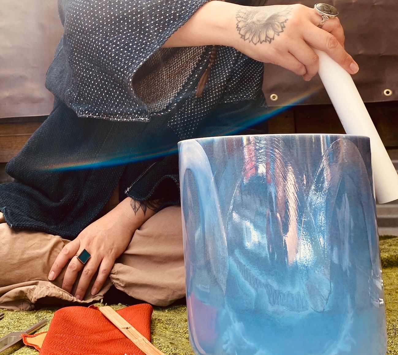 A person sitting cross-legged ringing a singing bowl for a sound bath.