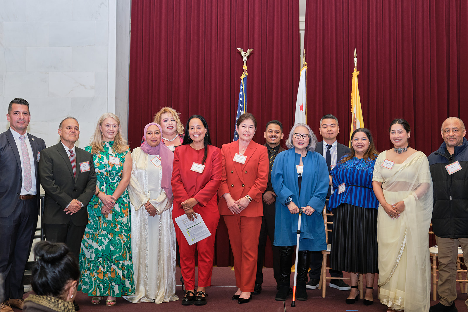 Immigrant Rights Commissioners smile on stage at the Immigrant Leadership Awards at San Francisco City Hall.