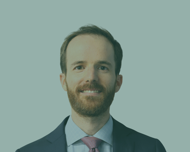 Mike Levine, HSH Executive Director wearing business attire standing in front of a United States flag and a light‑colored backdrop.