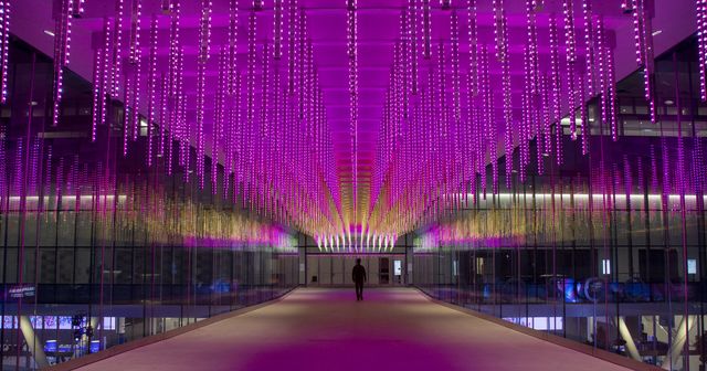 Overhead pedestrian walkway lit up with dangling magenta pink icicle lights.