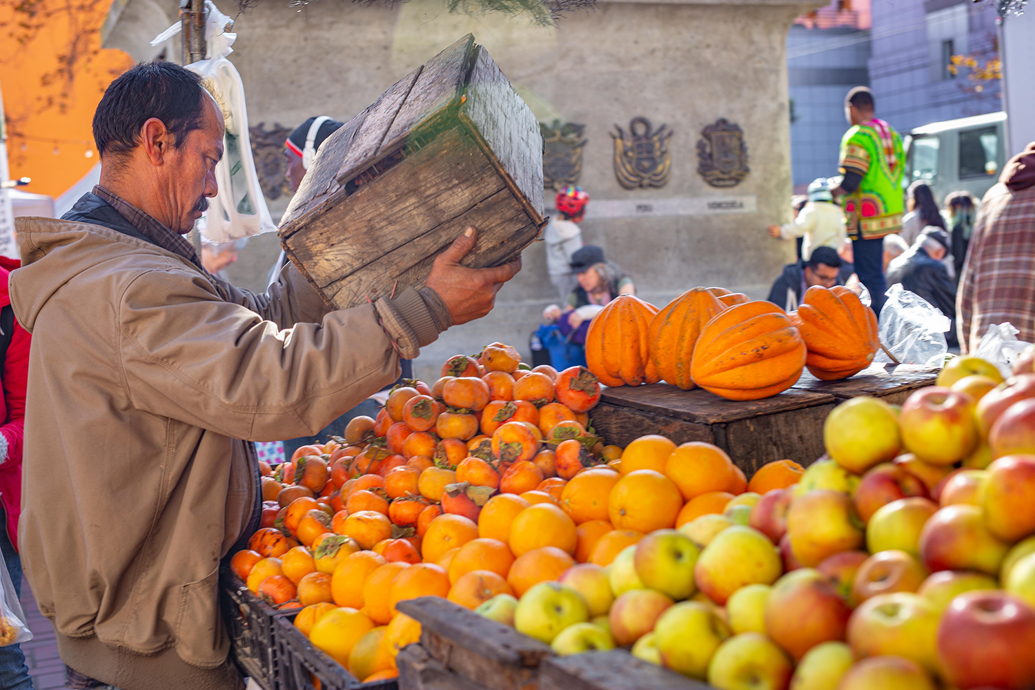 Man emptying a crate of fruit at a farmers market.
